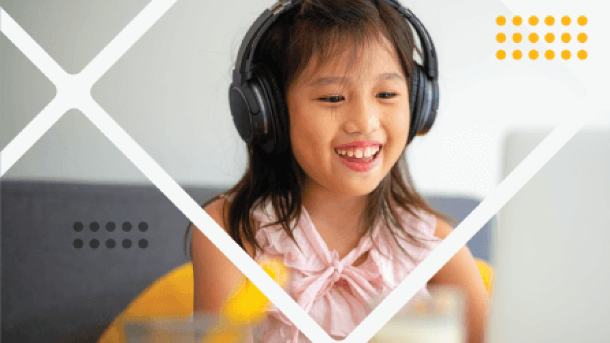 Young girl with brown hair wearing headphones and pink shirt smiles broadly while typing on laptop